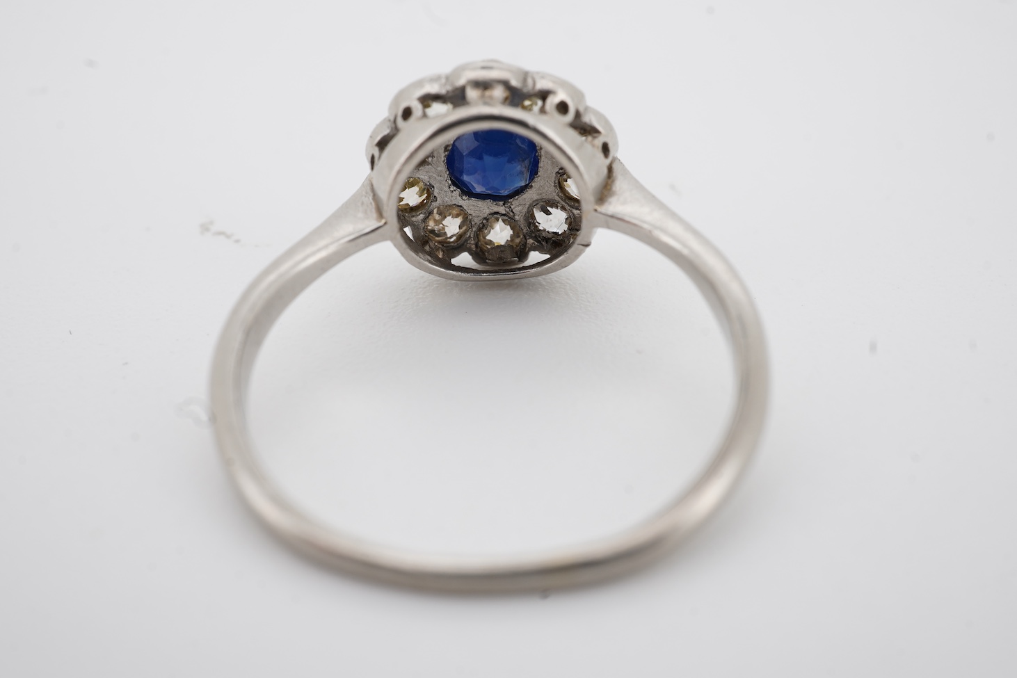 A 1920's white metal(stamped plat), sapphire and diamond set circular flower head cluster ring, size J, gross weight 2.7 grams.